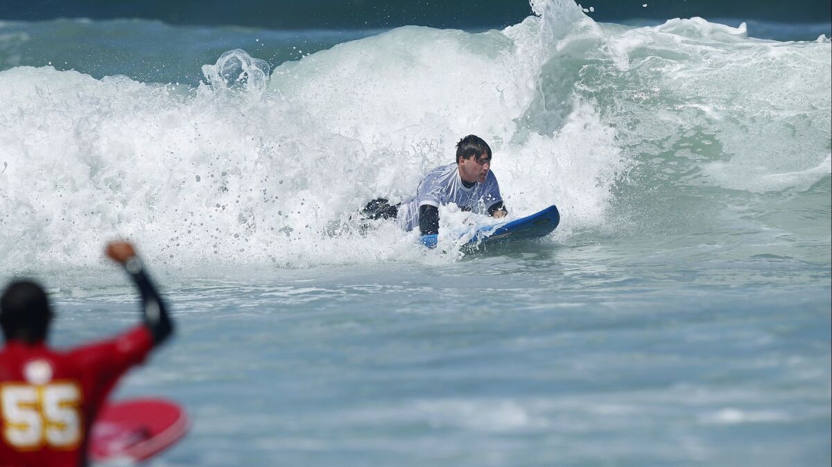 Isaac Coulapides, a Mt. Carmel High student who was paralyzed after a car accident last fall, surfs during a youth adaptive surfing camp in Del Mar on Thursday.