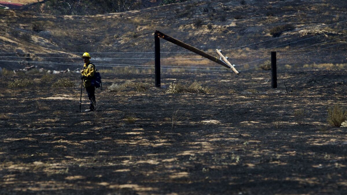 A firefighter checks on hot spots after the Manzanita fire burns 5,800 acres of rugged terrain and knocked down power poles off Highland Springs Avenue south of Beaumont.