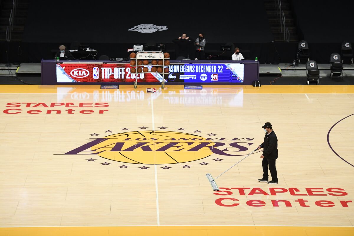 A Staples Center staff member cleans the court before a preseason game between the Clippers and Lakers on Dec. 13, 2020.