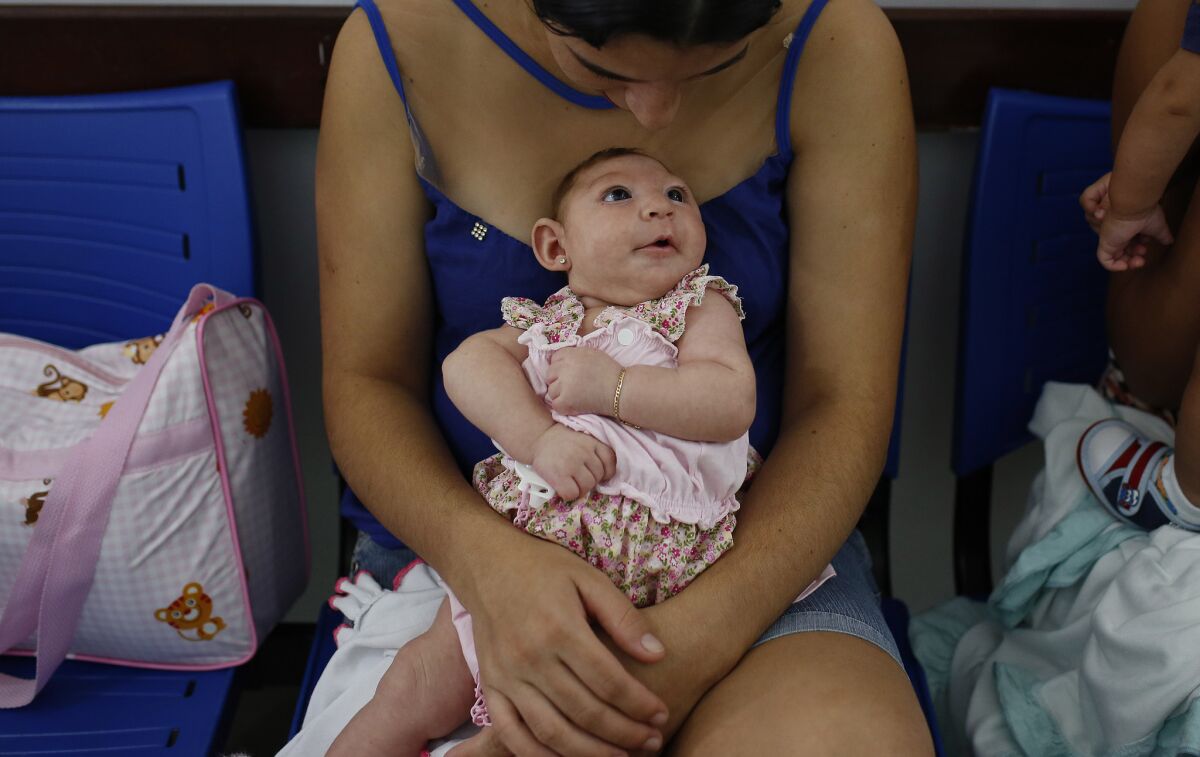 A mother holds her daughter, who was born with microcephaly