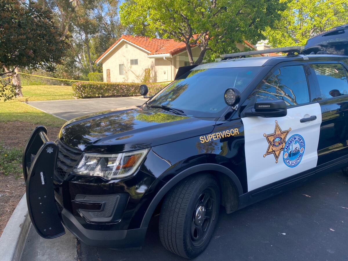 A police SUV parked outside a suburban home with yellow crime scene tape