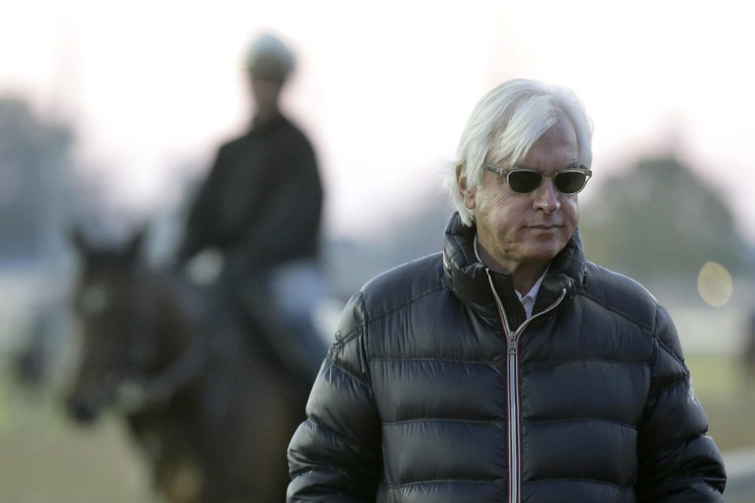 Trainer Bob Baffert walks along the track while one of his horses cools down from a workout.