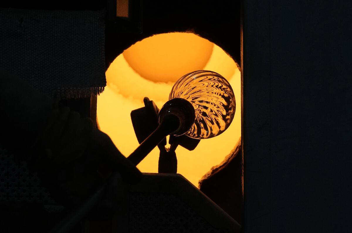 Un vidriero calienta en un horno una creación en un taller de cristales de Murano, Italia