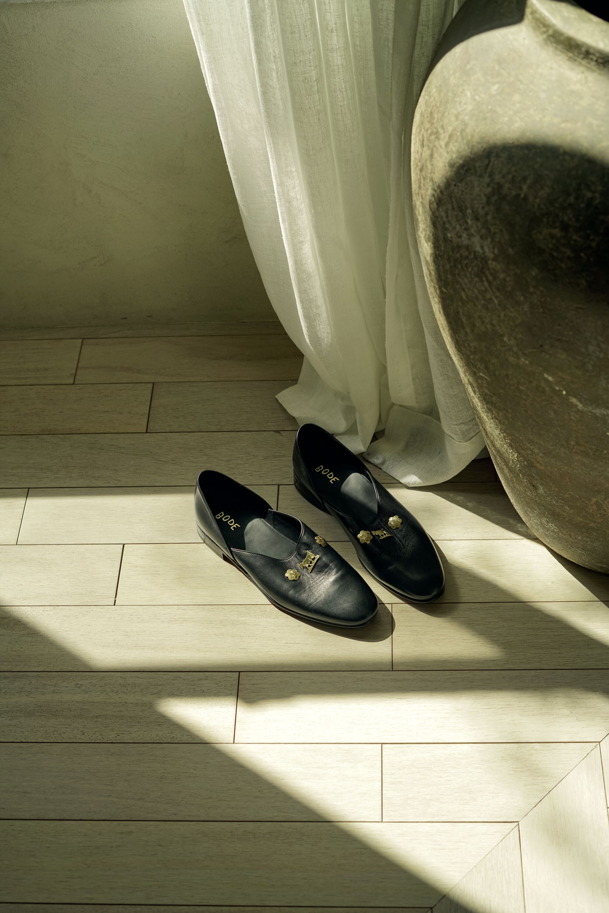 A pair of black house shoes in a home, bathed in soft light.