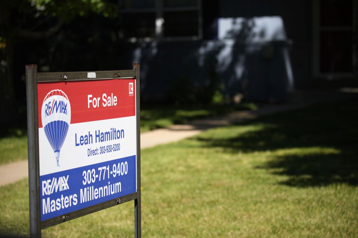 A sale sign stands outside a home on the market.