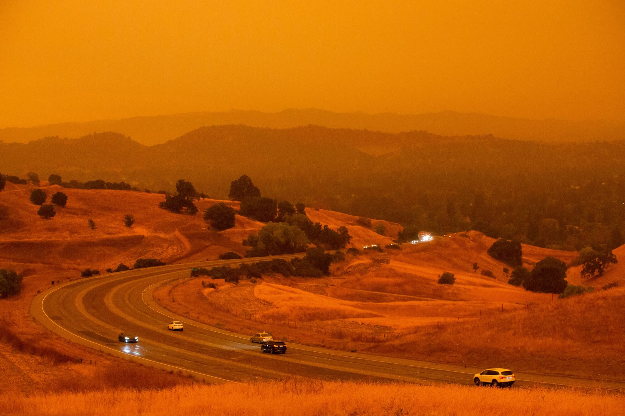 Cars on Ygnacio Valley Road in Concord, under a sky tinted orange by wildfire smoke.