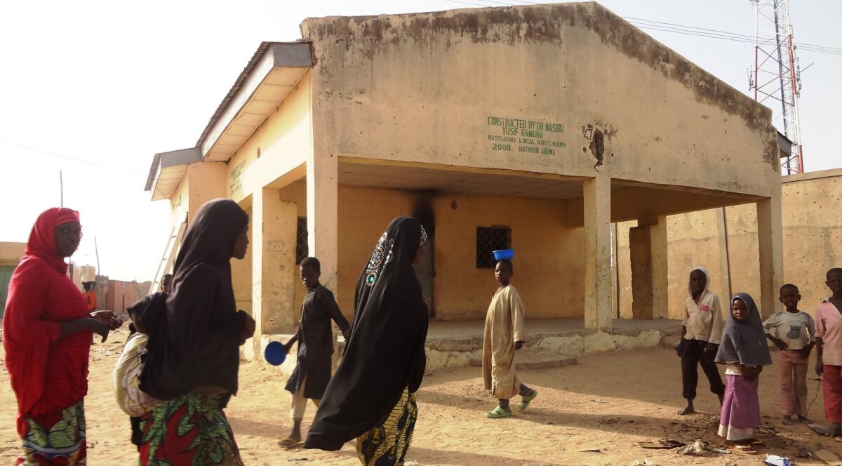Women pass the dispensary in the northern Nigerian city of Kano where gunmen killed nine polio immunization workers. Two radio journalists are being held on suspicion of inciting the violence.