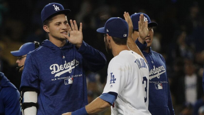 Dodgers shortstop Corey Seager, left, greeting Chris Taylor after a game last season, is targeting opening day to return from elbow and hip surgeries.
