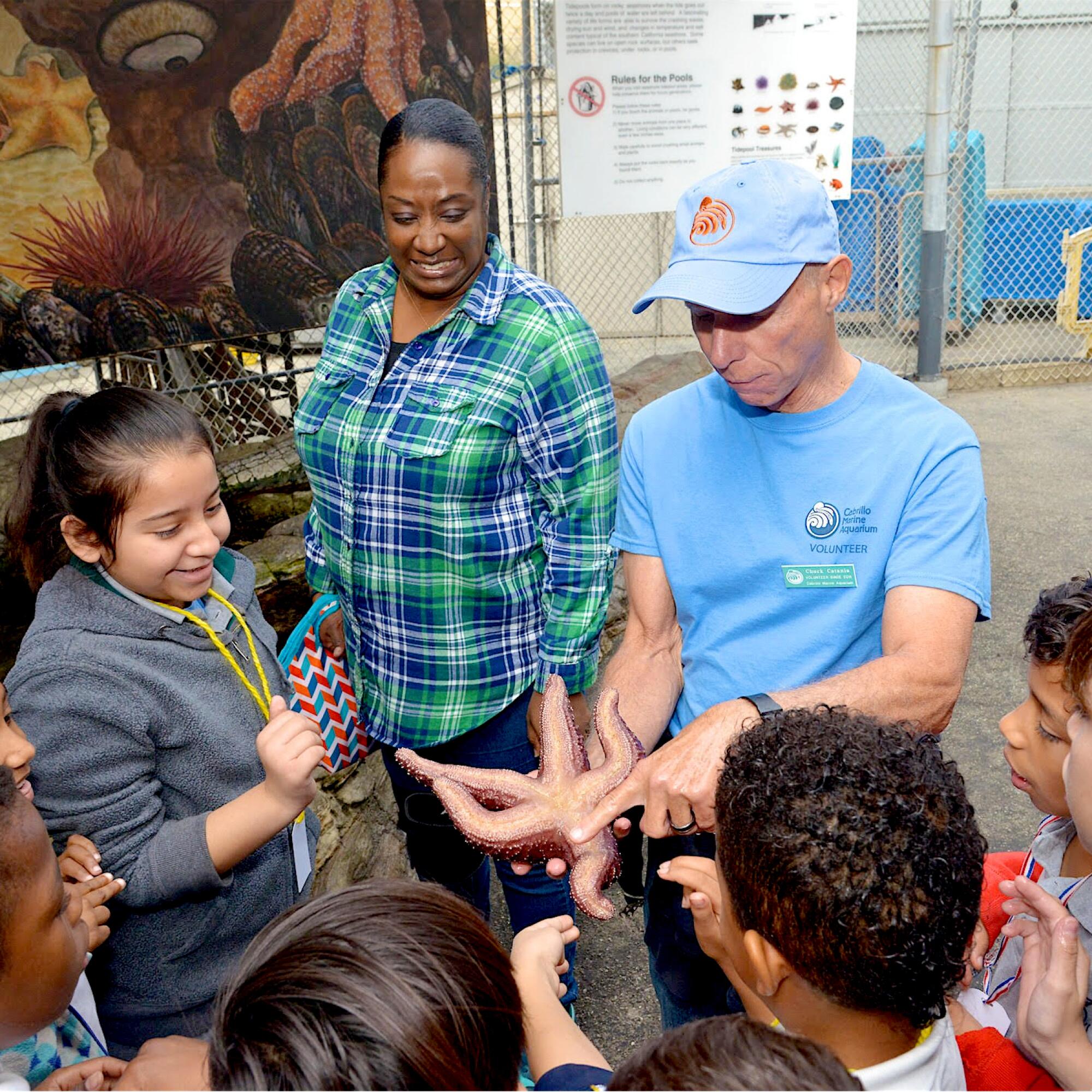 A man shows a sea star to students at the Cabrillo Marine Aquarium in San Pedro.