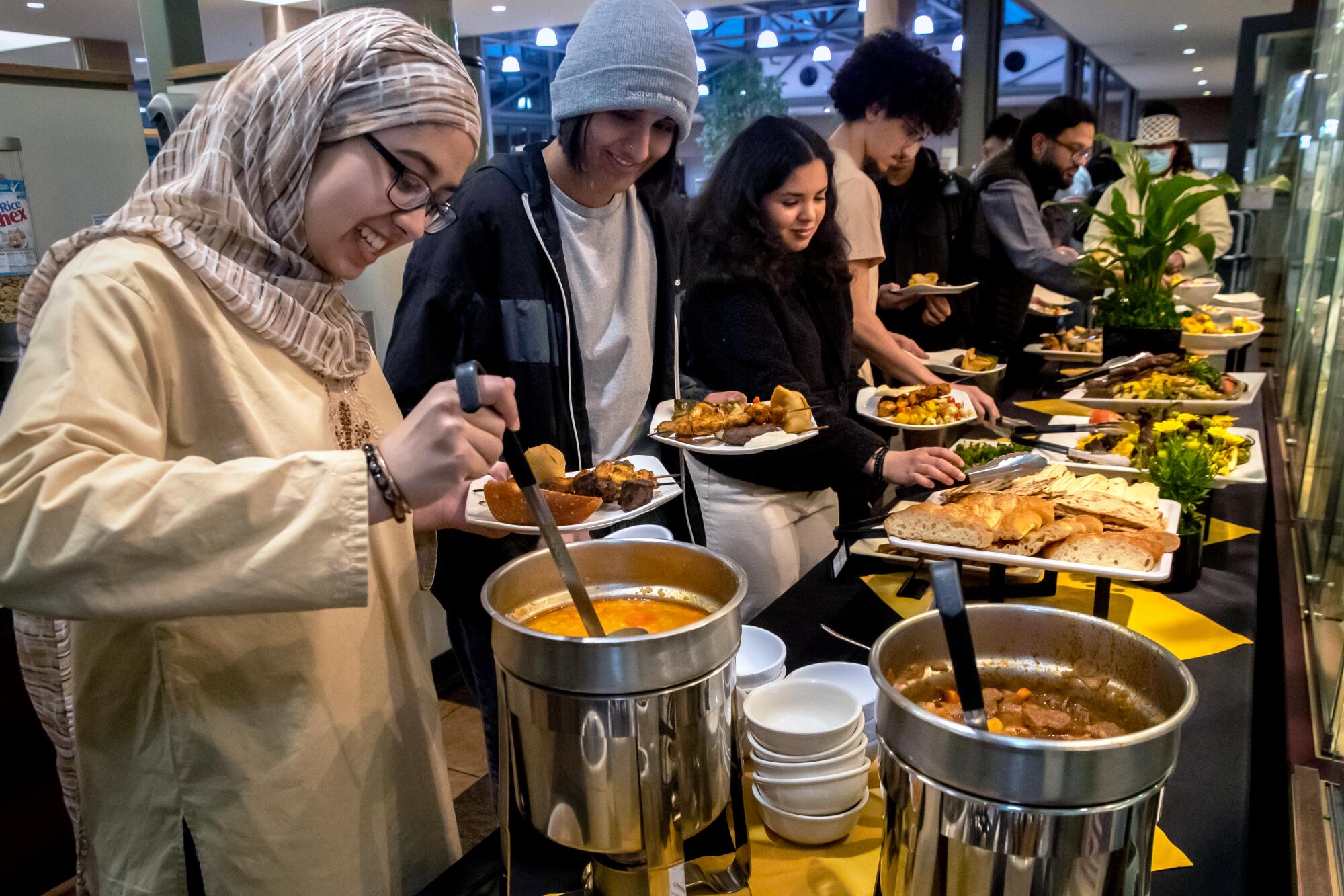 Students line up next to a long table loaded with food to partake in specially prepared halal meal for Muslims 