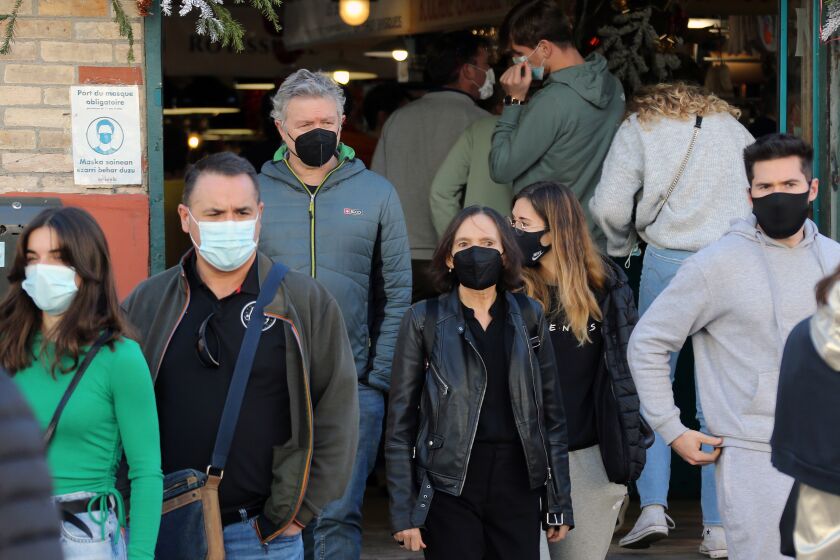 People wearing face mask walk on the street in Saint Jean de Luz, southwestern France, Thursday, Dec.30, 2021. The French government announced this week new measures to fight the spreading of the virus as France reported a record high of 208,000 new infections on Wednesday. Mask-wearing is already mandatory inside shops, public facilities, office buildings and public transports across France. (AP Photo/Bob Edme)