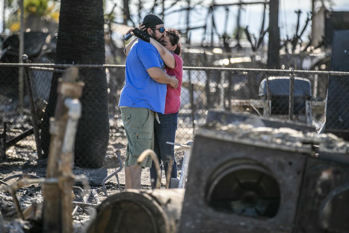 Guadalupe and Daniel Altamirano comfort each other as they survey the ashes of their cousin's home in Niland, Calif.