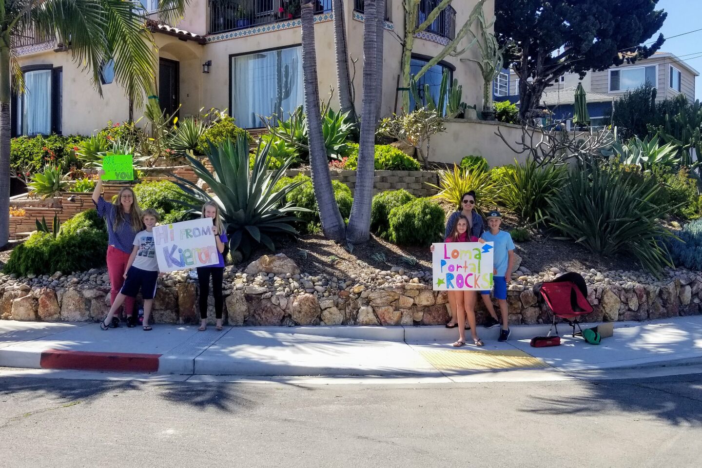 The McAteer family (left) and their neighbors the Brown family (right) stand on the corner, ready to wave to Loma Portal teachers.