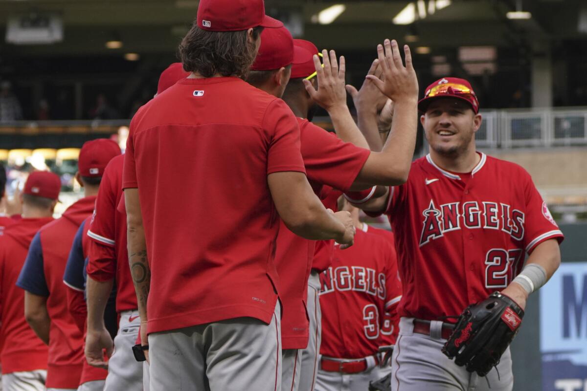 Mike Trout, right, smiles as he moves through the celebration line after the Angels' 10-3 win over the Minnesota Twins.