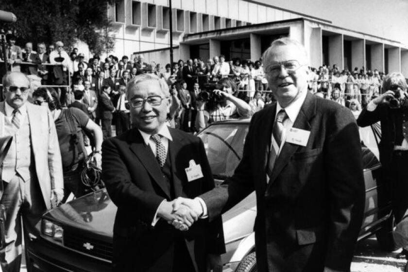 FILE - In this April 13, 1985 file photo, Toyota Motor Corp. Chairman Eiji Toyoda, left, and General Motors Corp. Chairman Roger B. Smith shake hands in front of a Chevrolet Nova as the new United Motor Manufacturing Inc., a $400 million joint venture between GM and Toyota, was inaugurated with a dedication ceremony at the Fremont, Calif., plant. (AP photo/Paul Sakuma, File)