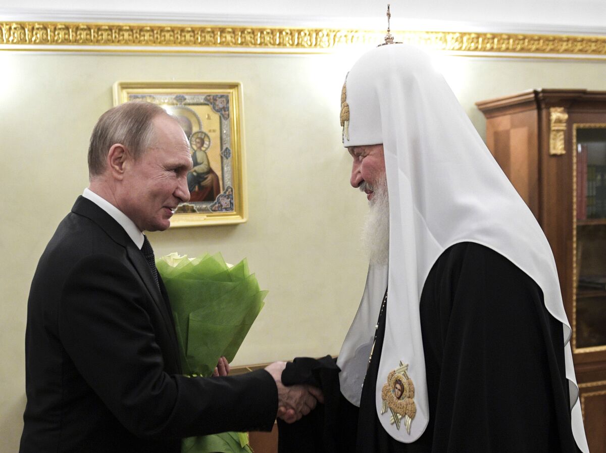 Vladimir Putin shakes hands with Russian Orthodox Patriarch Kirill.