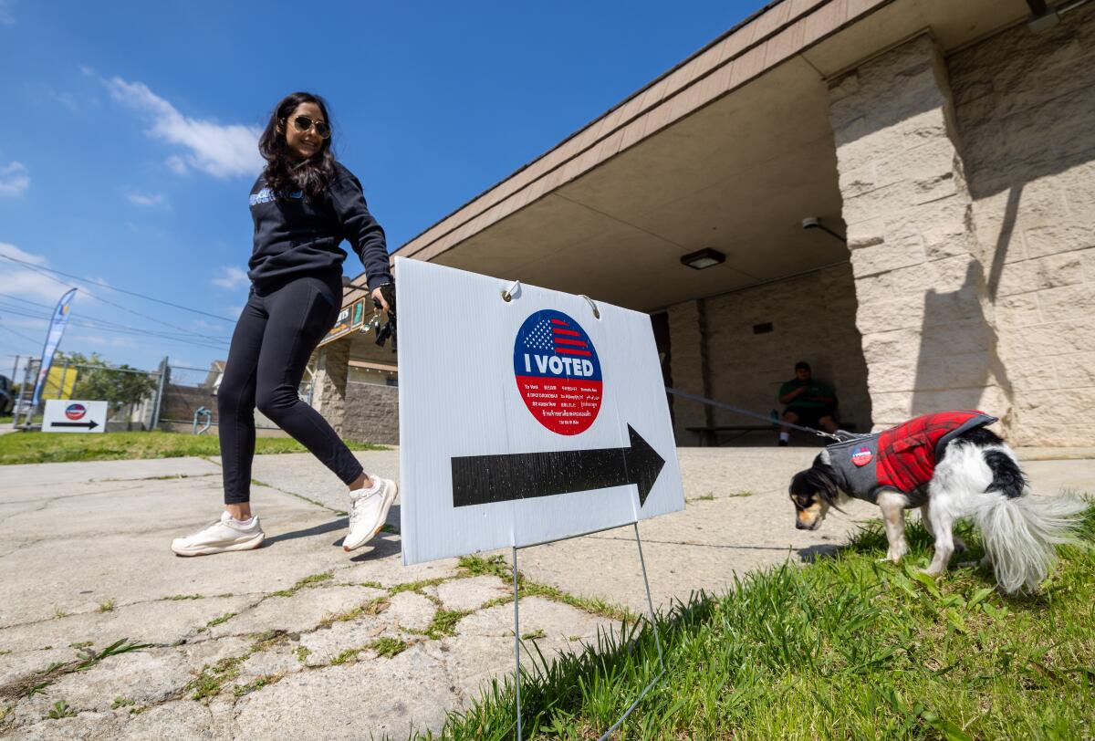 A woman leaves a polling place with her dog.