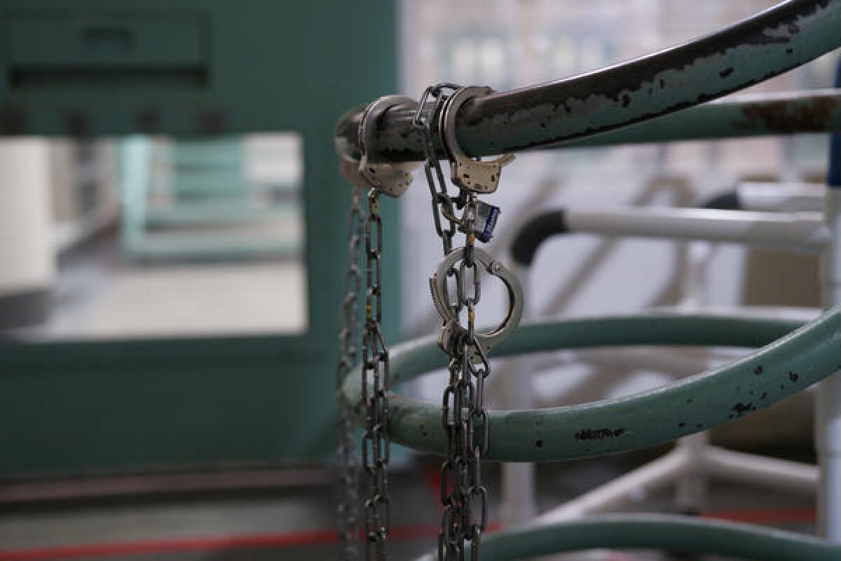 Handcuffs hang from a railing inside a jail facility