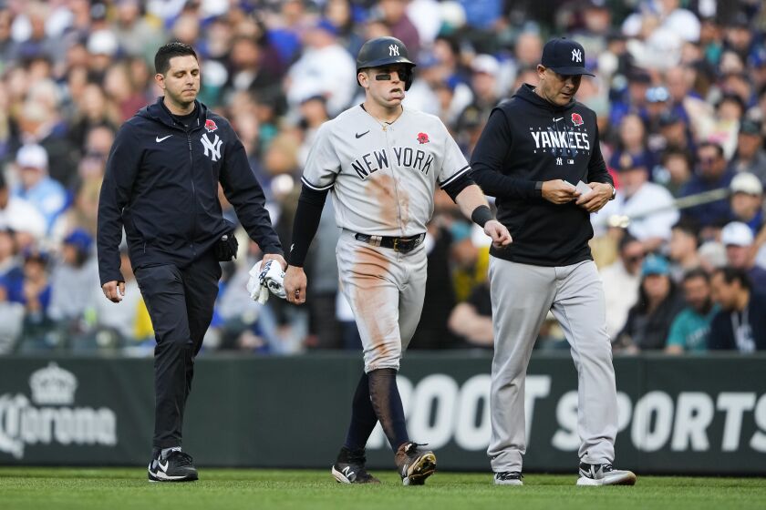 New York Yankees' Harrison Bader, center, leaves a baseball game with an apparent injury while accompanied by a trainer, left, and manager Aaron Boone, right, during the third inning of a baseball game against the Seattle Mariners, Monday, May 29, 2023, in Seattle. (AP Photo/Lindsey Wasson)