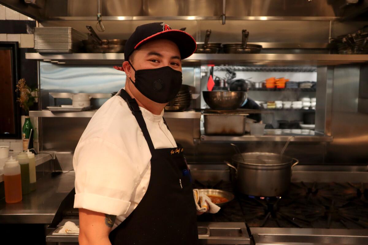 A masked employee stands in the kitchen at the Blind Pig Kitchen and Bar.