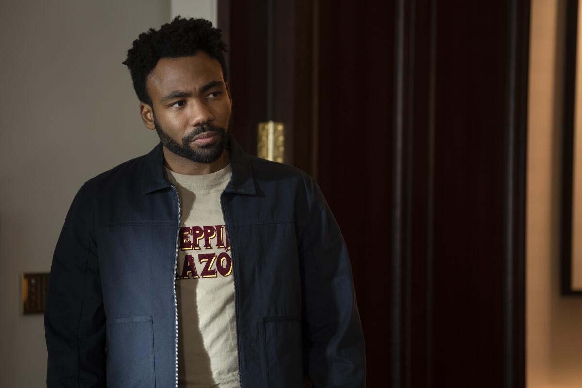 Donald Glover, con una chaqueta azul, mirando hacia un lado.