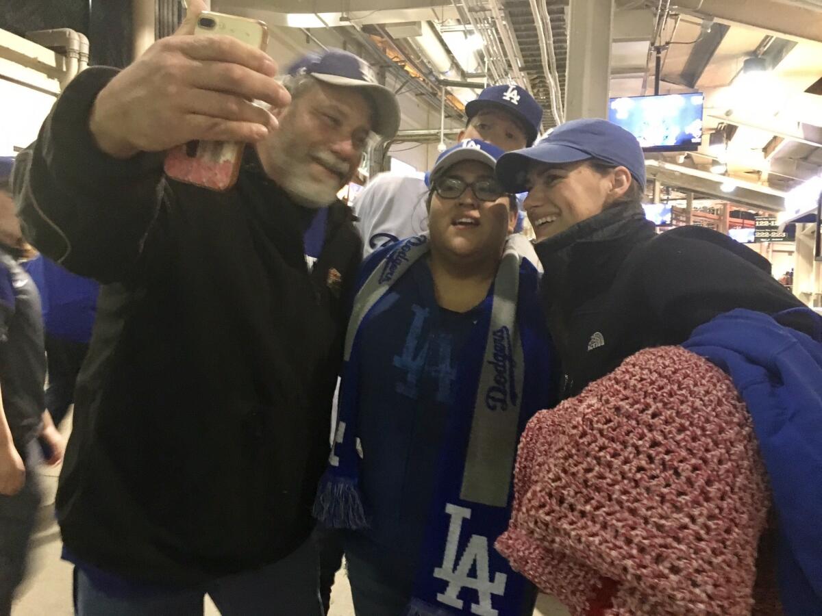 Don Hundoble, left, and Mehgin Lawrence are joined in a selfie by strangers in Dodgers gear.
