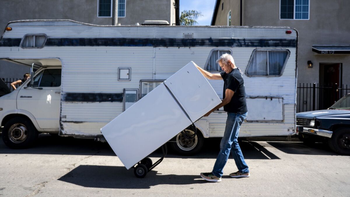 John Betz rolls a refrigerator down Wall street on March 6 as he and Heidi Roberts set up units in South Los Angeles to be leased exclusively to homeless people.