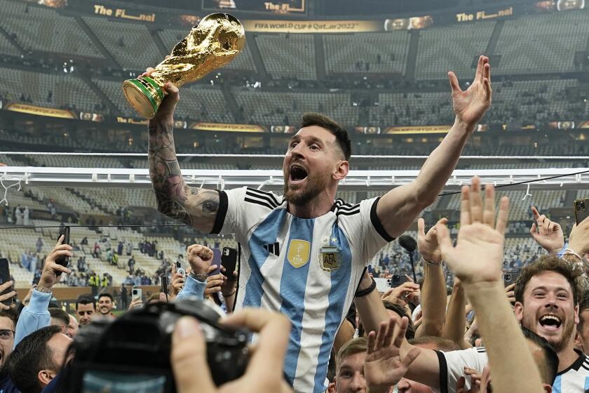 Argentina's Lionel Messi celebrates with the trophy in front of the fans after winning.