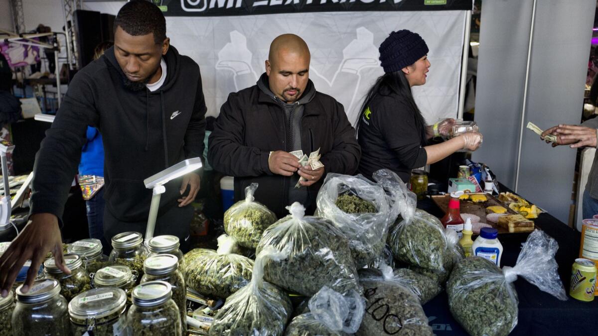 Vendors from MF Extracts count cash at their booth at a marijuana festival in Adelanto, Calif., in December.