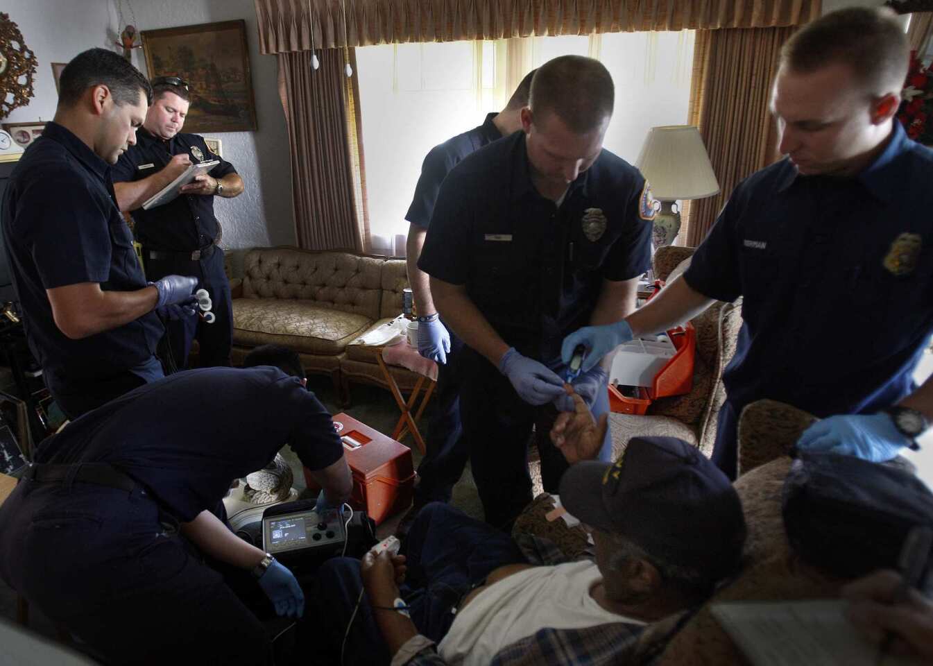 Los Angeles County firefighters and paramedics take the vital signs of Nathan Shands, 90, whose family called 911 because he had been throwing up and they couldn't get him in the car. Shands was taken to St. Francis Medical Center in Inglewood by private ambulance.