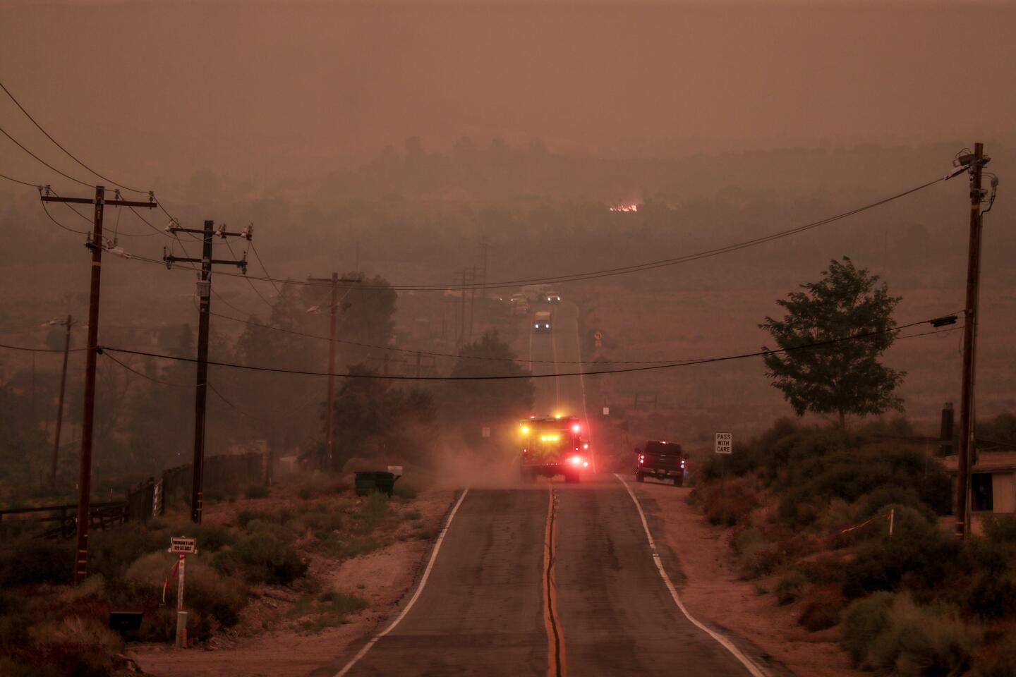 A fire engine drives on a smoky road in the Antelope Valley