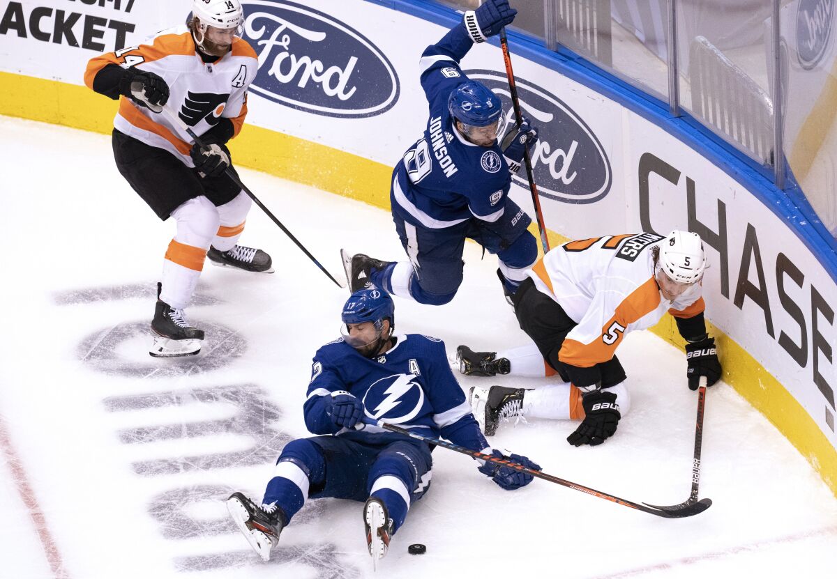 Tampa Bay Lightning left wing Alex Killorn, bottom, and center Tyler Johnson (9) work for the puck against Philadelphia Flyers center Sean Couturier (14) and defenseman Philippe Myers (5) during the second period of an NHL hockey playoff game Saturday, Aug. 8, 2020, in Toronto. (Frank Gunn/The Canadian Press via AP)