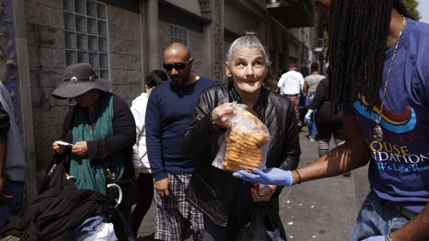 Volunteer King James hands out bread at a skid row food giveaway by My Friend's House Foundation in April.