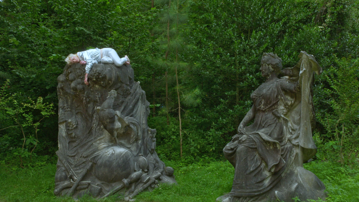A person sleeps on a statue.