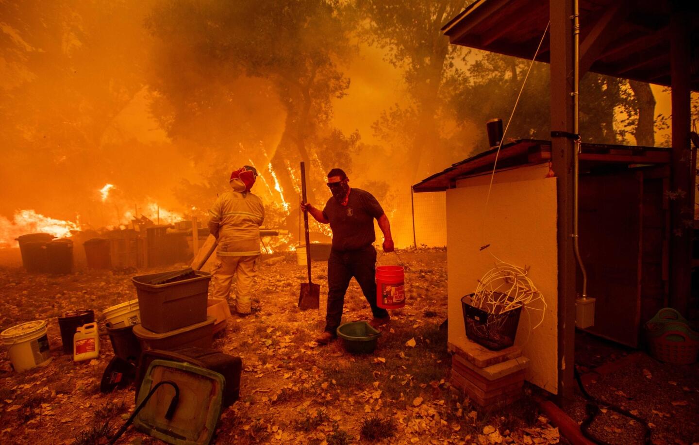 Resident Lane Lawder carries a water bucket while fighting to save his home from the Ranch fire burning along New Long Valley Road near Clearlake Oaks.