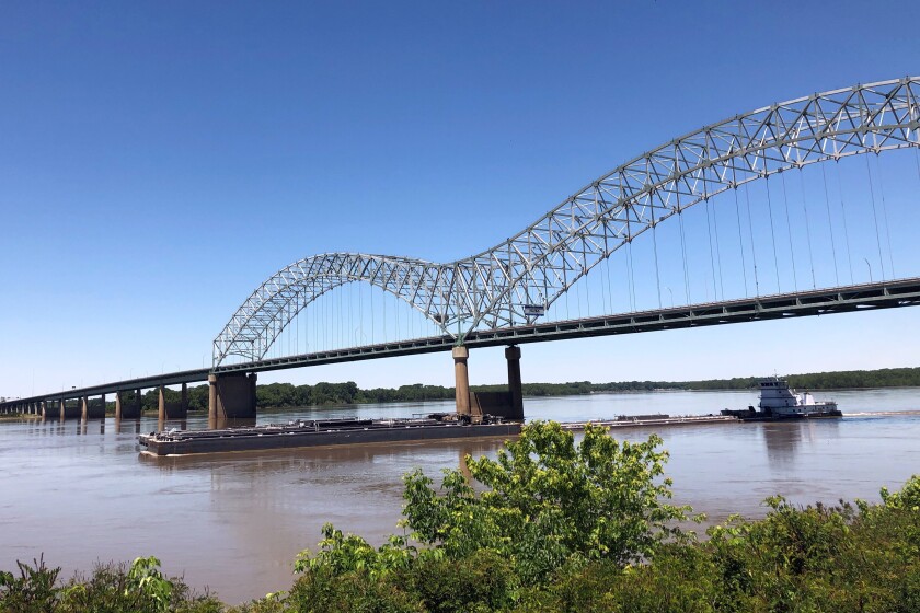 A tug boat pushes barges down the Mississippi River and under the Interstate 40 linking Tennessee and Arkansas on Friday, May 14, 2021, in Memphis, Tenn. The U.S. Coast Guard reopened a section of the river near Memphis on Friday, three days after river traffic was shut down when a crack was found in the bridge. (AP Photo/Adrian Sainz)