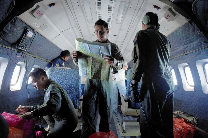 A member of the Malaysian air force consults a map aboard a military aircraft as the crew takes part in the search for a Boeing 777 that disappeared last weekend with 239 people aboard. Thirteen countries are involved in the effort.