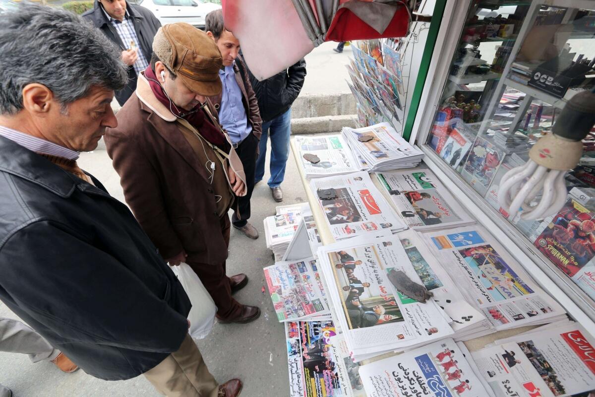 Iranians look at newspapers displayed outside a kiosk in Tehran after an interim deal was reached on the country's nuclear program.