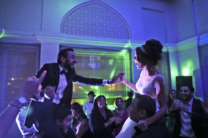 Israeli couple Noemie Azerad, right, and her husband Simon David Benhamou grasp each others hands on the shoulders of skullcap-wearing groomsmen during their wedding party at a hotel in Dubai, United Arab Emirates, Thursday, Dec. 17, 2020. For the past month, Israelis long accustomed to traveling incognito, if at all, to Arab countries, have made themselves at home in the UAE’s commercial hub.(AP Photo/Kamran Jebreili)