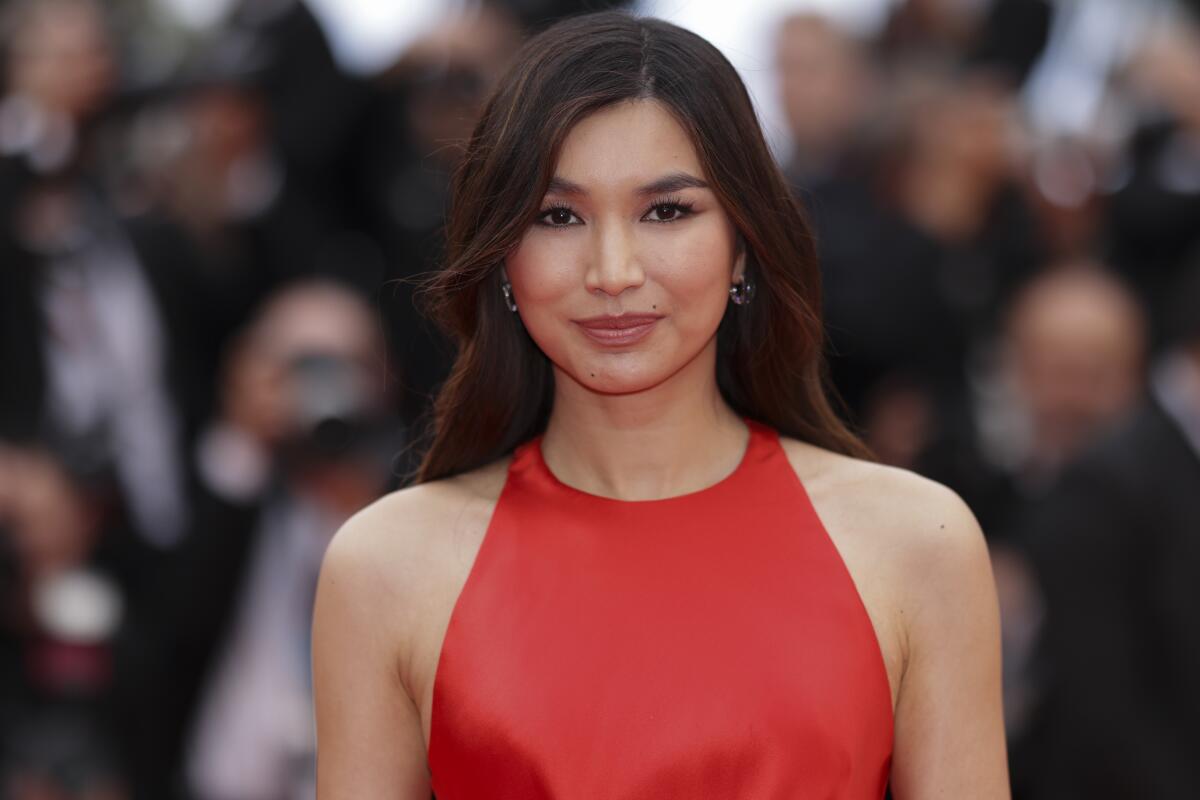 Gemma Chan wears a red dress as she poses for photos at a movie premiere