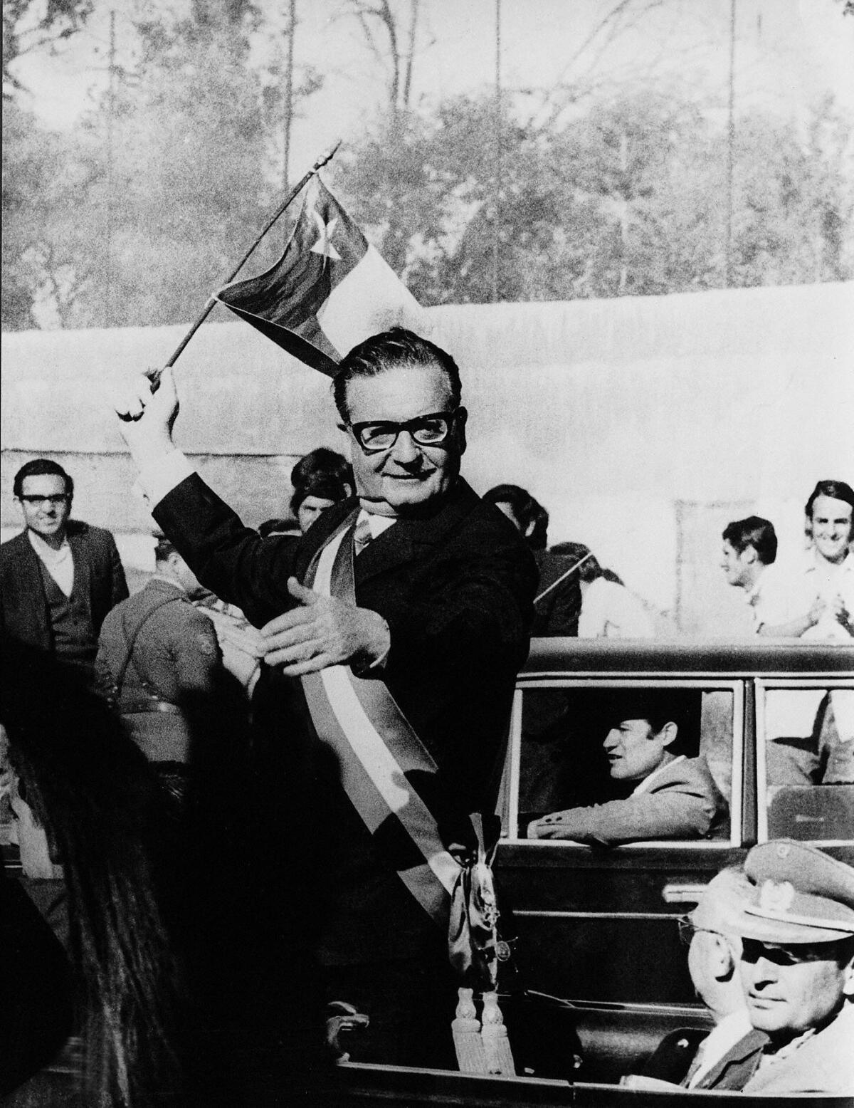 Black-and-white photo of Salvador Allende waving a Chilean flag