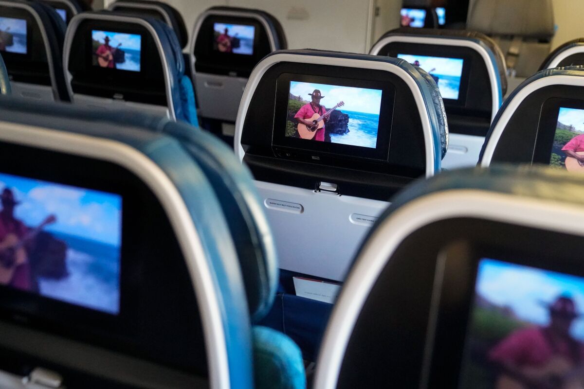 As a Hawaiian Airlines flight from LAX nears Honolulu, seatback screens show an island musician.