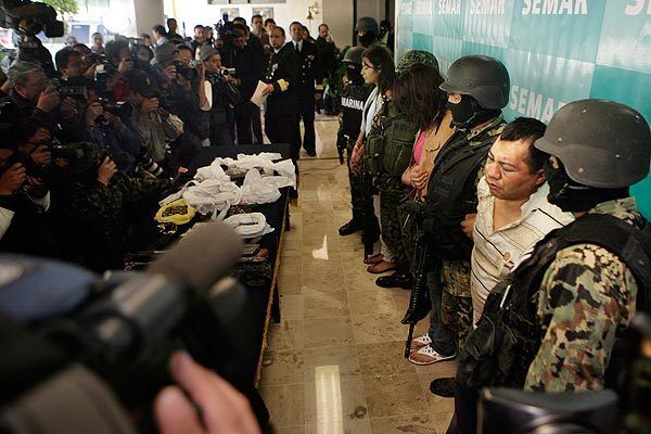 Mexican soldiers escort Gabriela Vega, far left, Catalina Castro Lopez, center, and an unidentified man during their presentacion in Mexico City. Critics say the media events violate suspects' rights.