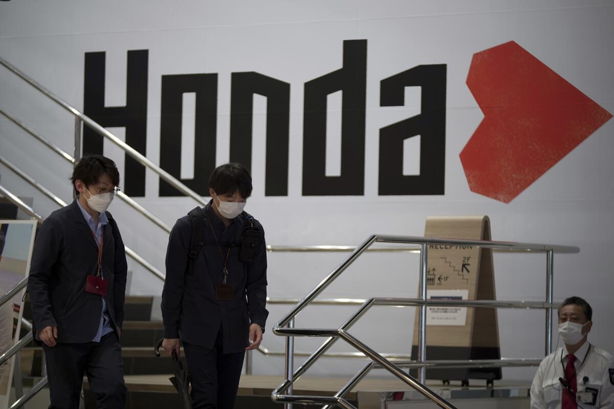 People walk near a Honda logo at a showroom in Tokyo.