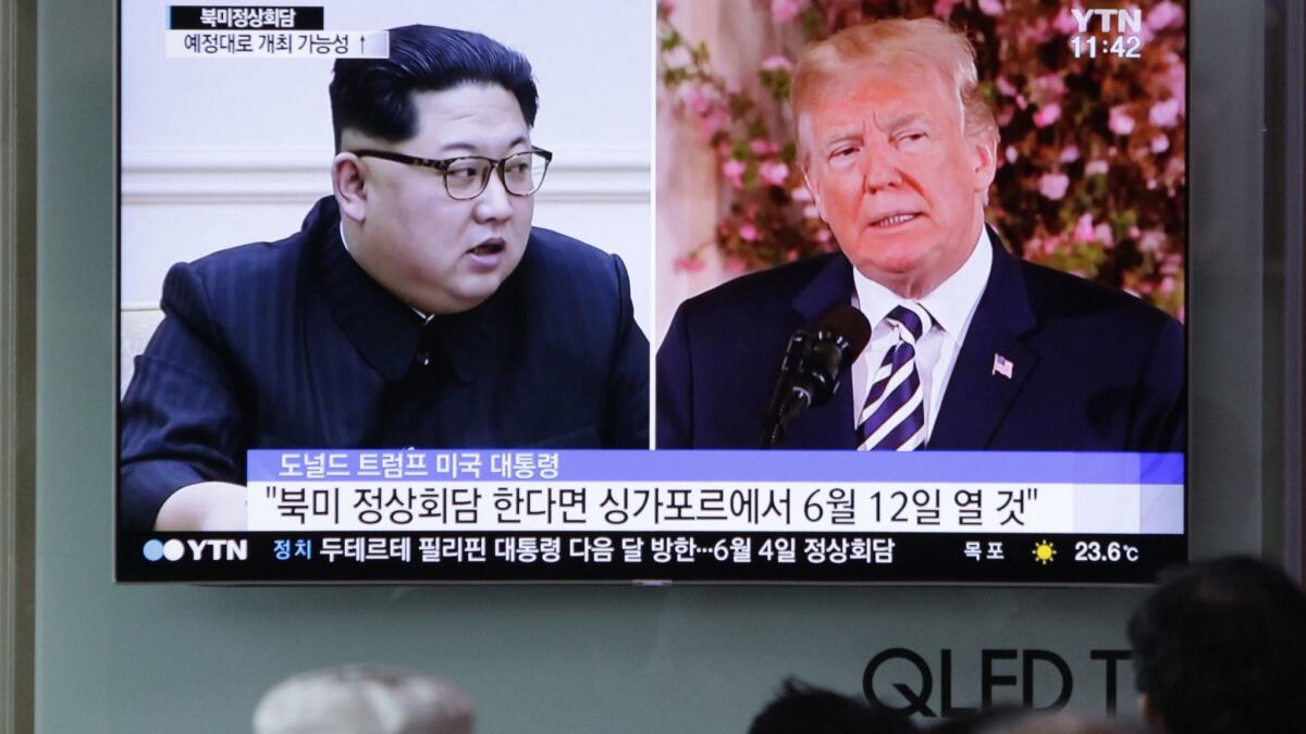 People watch a TV screen on May 26 showing file footage of U.S. President Donald Trump and North Korean leader Kim Jong Un during a news program at the Seoul Railway Station in Seoul, South Korea.
