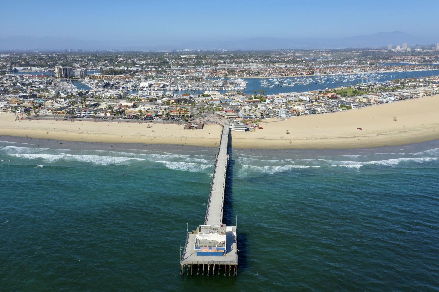 An aerial view of the Newport Beach pier, where a few surfers and beach-goers enjoy a nice day at the beach despite Gov. Gavin Newsom's hard closure, which is still in place in Newport Beach.