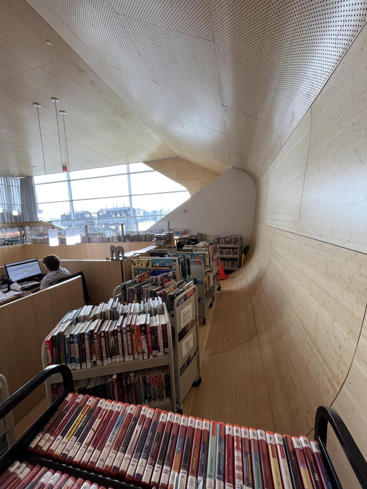 Carts pile up at the base of a curving wooden wall in a library children's area