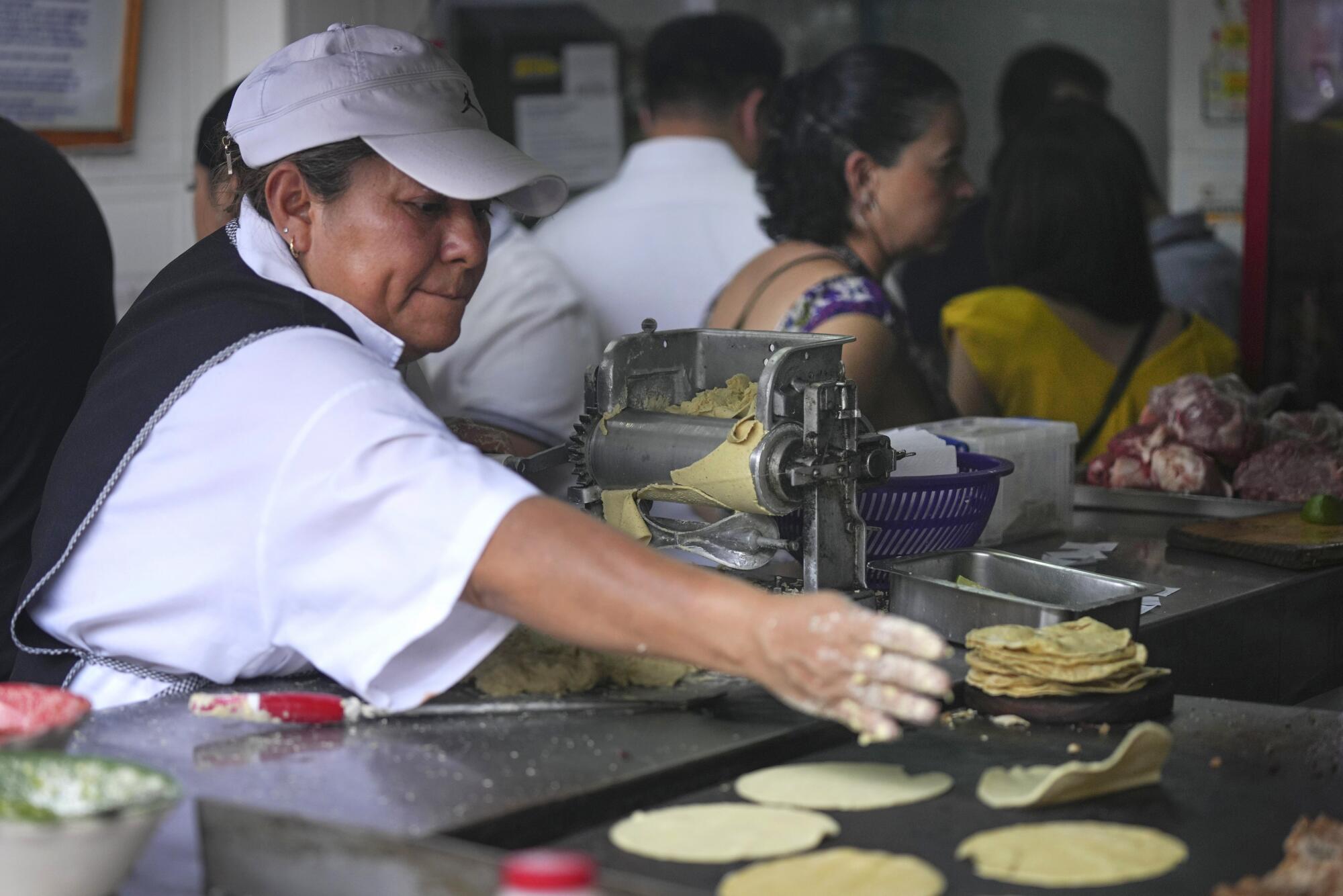 An employee tosses a tortilla on a griddle at El Califa de 尝别ó苍.