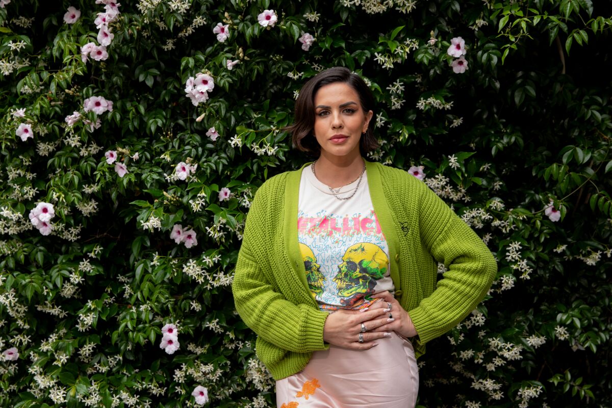 Katie Maloney posing for a portrait in front of a flower bush.