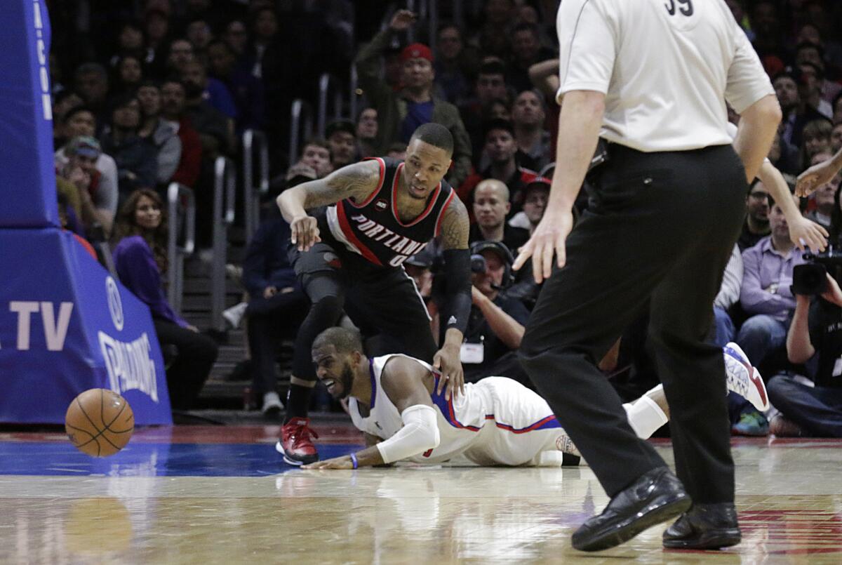 Clippers point guard Chris Paul dives on the ground for a loose ball battling with Trail Blazers point guard Damian Lillard in the second half.